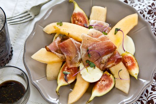 Fig,Cantaloupe with Prosciutto and Mozzarella salad [ Antipasti ] with purple sprout on top by Balsamic dressing