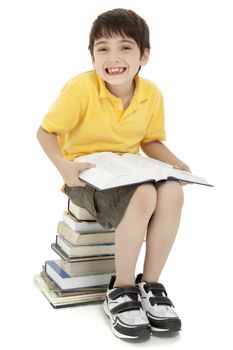 Excited elementary age school boy child sitting on stack of books reading.