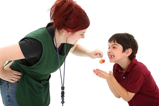 Attractive redhead 19 year old grocer clerk sharing cherries with 8 year old french boy making funny faces over white background.