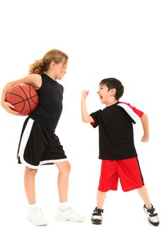 Adorable short boy child shaking fist at taller girl basketball player over white.
