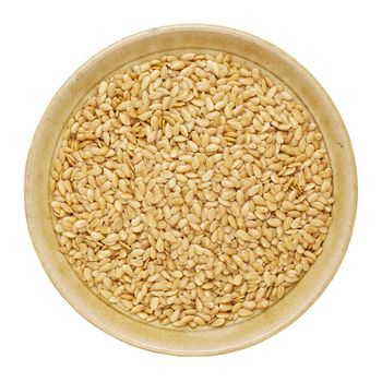 gold flax seeds in a round ceramic bowl isolated on white