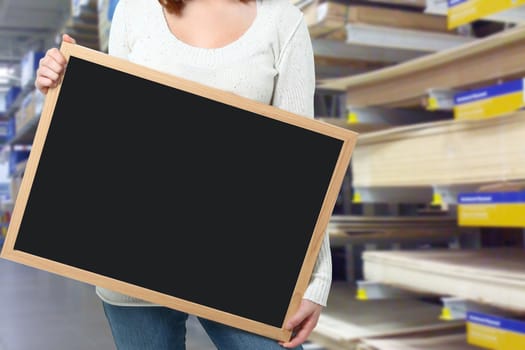 Young woman holding blank blackboard at a hardware store.