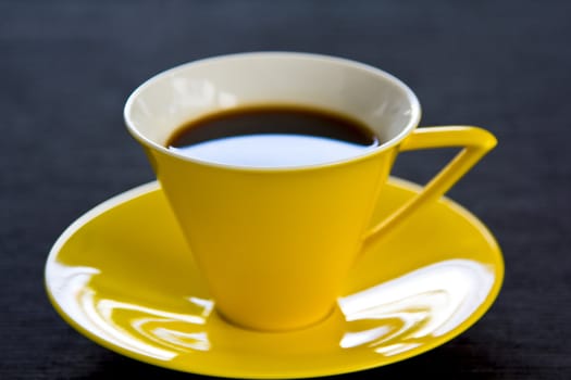 Black coffee in yellow cup and saucer