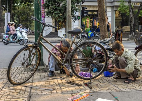 Small free enterprise vendor working on bicycle.