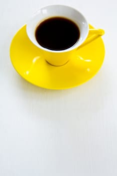 Black coffee in yellow cup and saucer