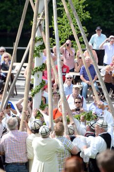 Maypole is raised with the help of thick reeds and the audience are watching