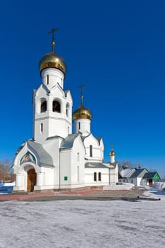 Church of white stone with domes on  background of blue sky.
