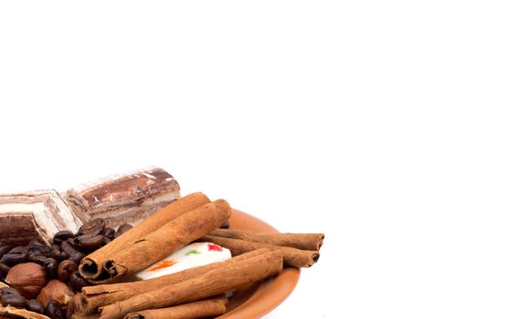 Sweets, cinnamon, nuts and coffee beans on a saucer isolated on white