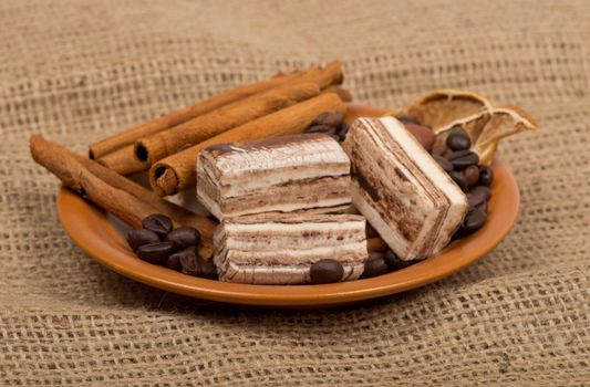 Sweets, cinnamon, nuts and coffee beans on a saucer.
