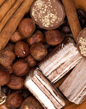 Sweets, cinnamon, nuts and coffee beans on a saucer, on burlap background.