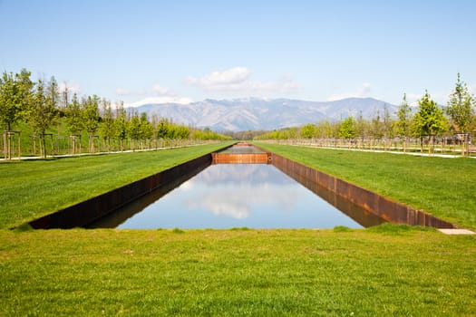 Italy - Water pool in green field with Alps mountains on background