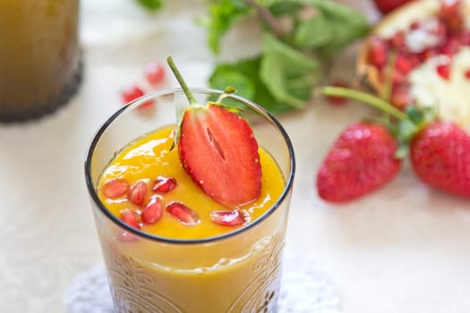 Mango and pineapple smoothie with fresh pomegranate and strawberry on top