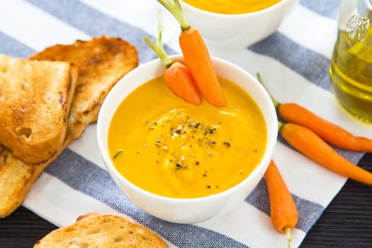 Carrot soup by some toasts and baby carrot