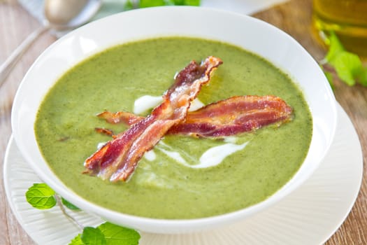 Pea,mint and celery soup with cream and bacon on top by a loaf of bread