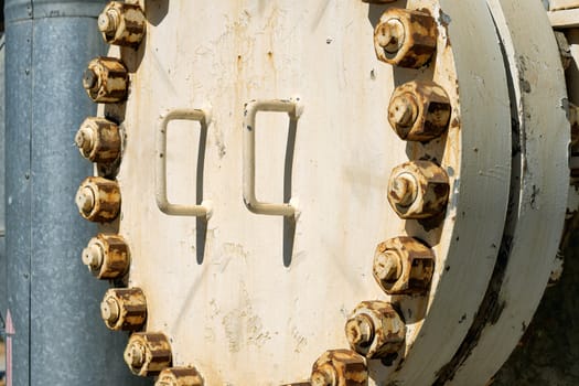 Tightly sealed heavy metal inspection plate with a ring of bolts around the circumference securing it to the main installation