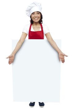 Full length portrait of young chef presenting billboard in front of camera