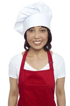 Young smiling female chef wearing red apron and toque