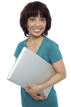 Casual woman carrying her laptop and smiling at camera