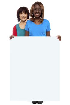Full length portrait of casual girls standing behind blank whiteboard