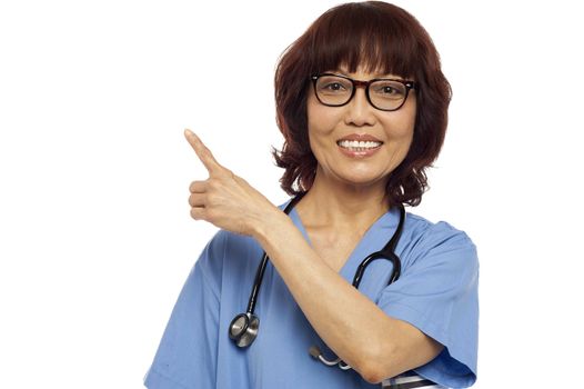Asian nurse pointing at the copy space. All on white background