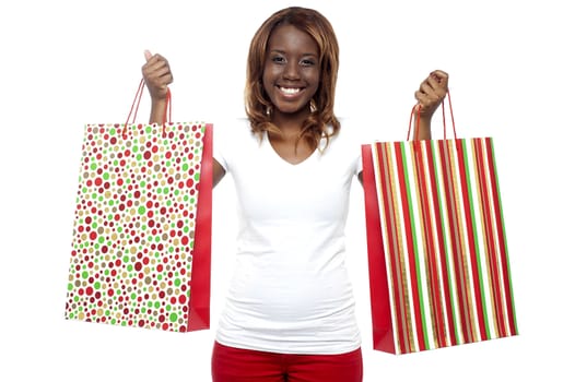 Shopaholic woman carrying shopping bags in both the hands isolated against white