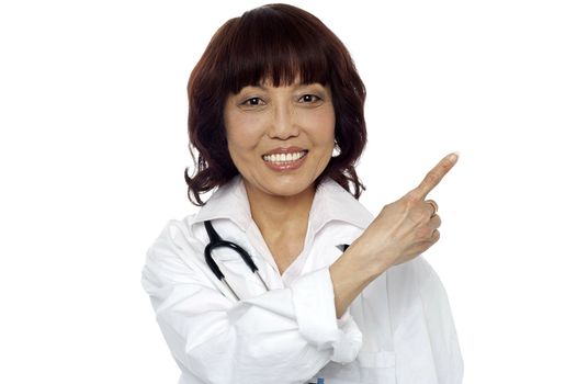Matured surgeon pointing at the copy space isolated over white background