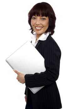 Asian corporate female holding laptop and smiling at camera