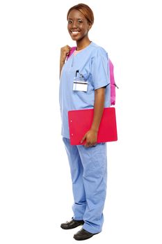 Junior female doctor under training. Ready to attend class holding backpack and clipboard