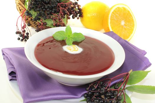 fresh elderberry soup with blobs of cream and mint on a light background