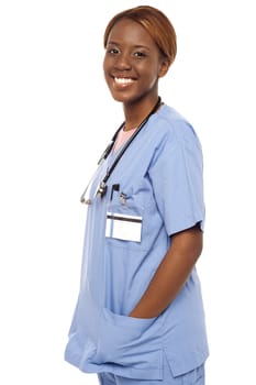 African female nurse posing casually in uniform. Hands in coat pocket