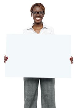 Female business executive holding blank billboard and showing it to camera