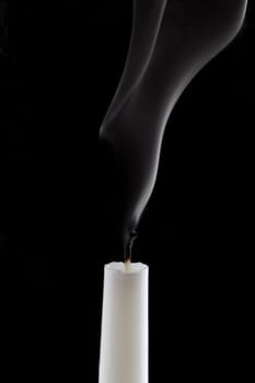 White candle with smoke on black background.