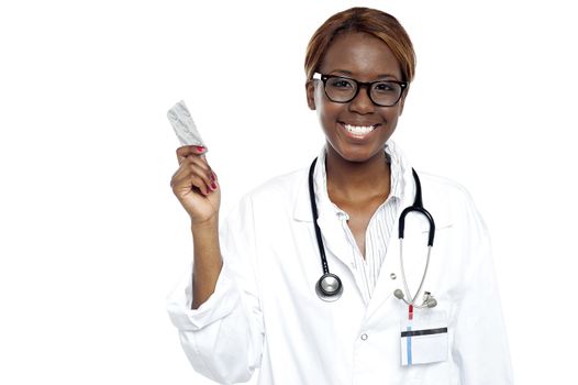 Female doctor holding pack of medicine. Looking at camera and smiling