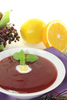 elderberry soup with dollop of whipped cream and mint on a light background