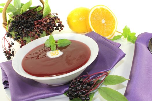 delicious elderberry soup with dollop of whipped cream and mint on a bright background