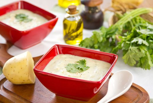 Potato soup with coriander by some potatoes and bunch of coriander