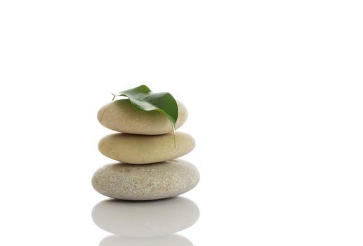 Spa stones and green leaf, isolated on white background.