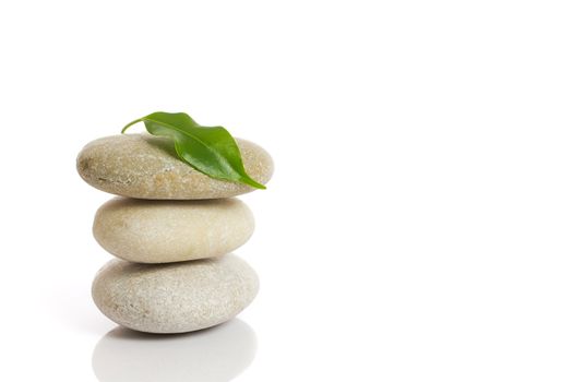 Spa stones and green leaf, isolated on white background.