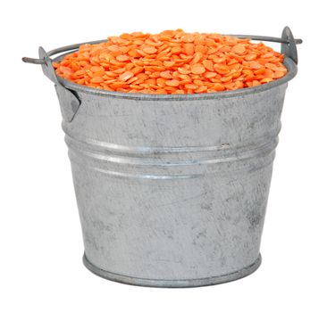 Red lentils in a miniature metal bucket, isolated on a white background