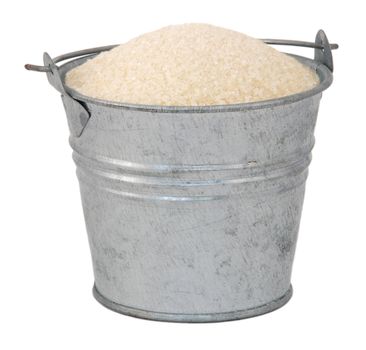 Golden granulated sugar in a miniature metal bucket, isolated on a white background