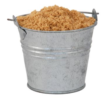 Light brown soft / muscovado sugar in a miniature metal bucket, isolated on a white background