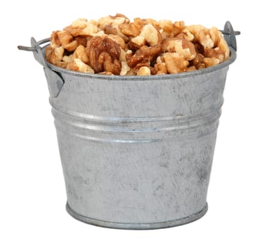 Chopped walnuts in a miniature metal bucket, isolated on a white background