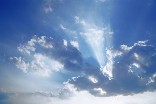 beams of the sun which are making the way through clouds in the blue sky