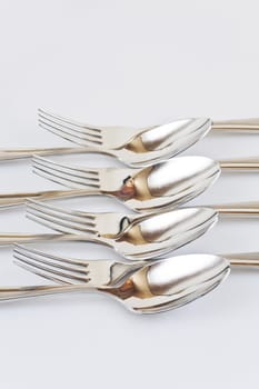 Set of forks and spoons abreast on a white background