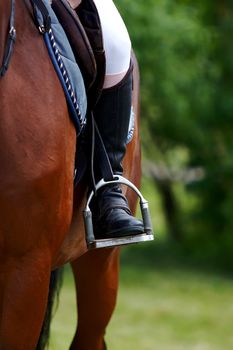 Foot of the athlete in a stirrup astride a horse