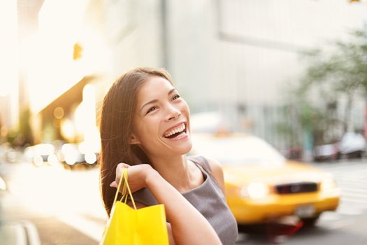 Shopper woman on Manhattan, New York City shopping having fun laughing outside in streets of New York. Fresh blissful mixed race Asian / Cauasian girl holding shopping bag.