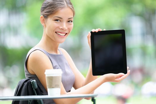 Tablet business woman showing display screen sitting in park. Beautiful young professional businesswoman smiling happy. Mixed race female model. Photo from Bryant Park, Manhattan, New York City.