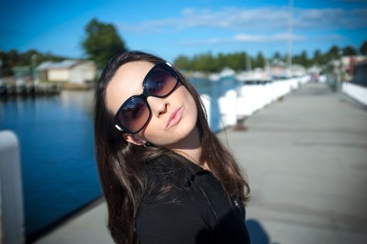 Young beautiful woman in sunglasses blow a kiss to you on the wharf