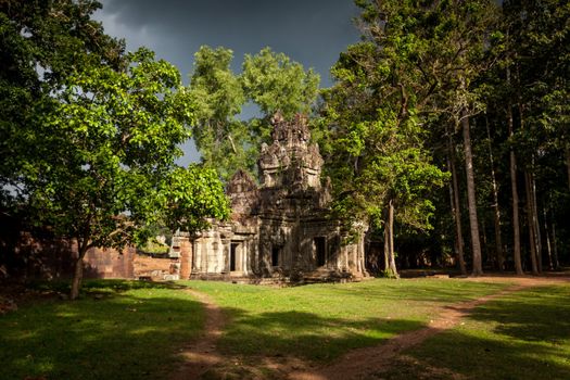 Vegetation growing out of Angkor ruin with stormy sky and sunshine