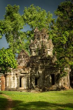 Vegetation growing out of Angkor ruin with stormy sky and sunshine